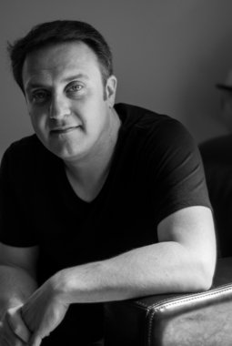 Black-and-white portrait of Jason Webb leaning on a leather chair