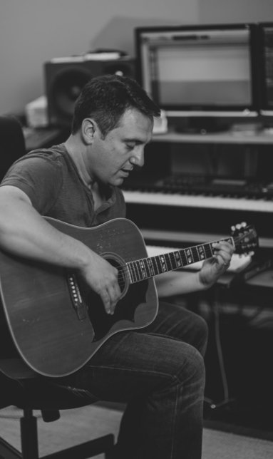 Jason Webb playing acoustic guitar in his studio